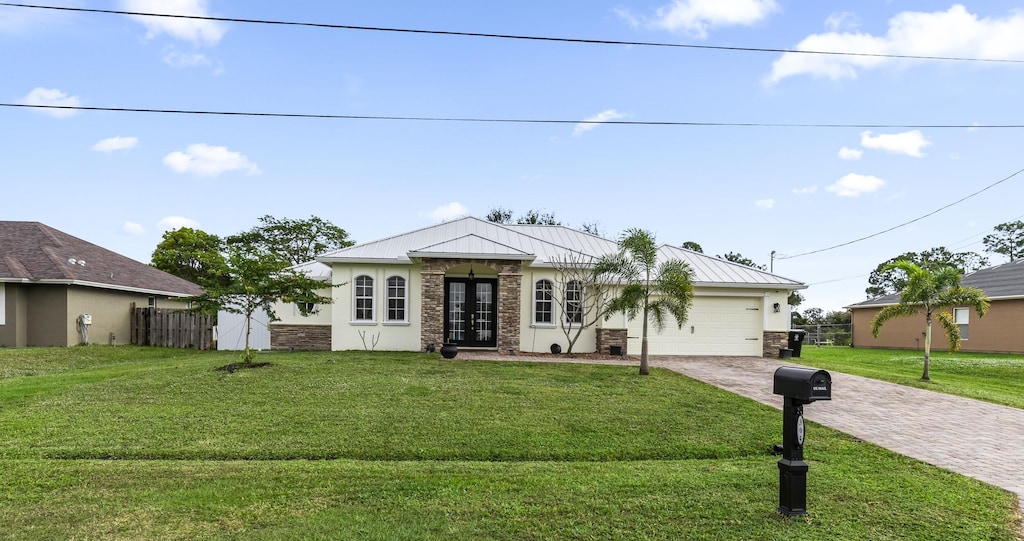 view of front facade featuring a garage, a front yard, and french doors