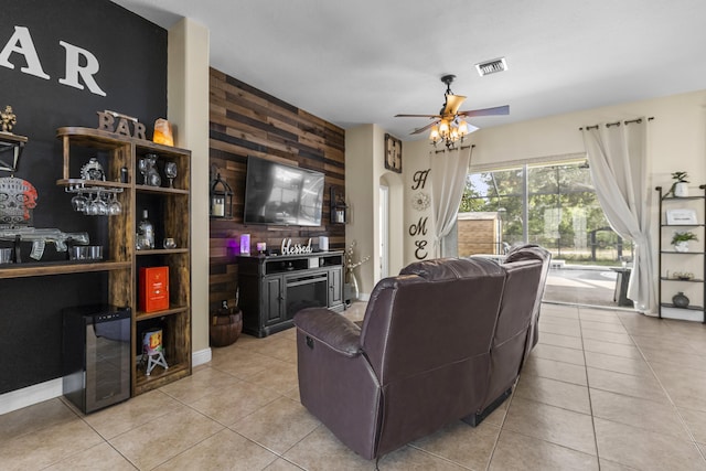 living room with ceiling fan, light tile patterned floors, and wood walls