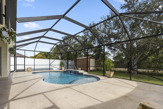 view of swimming pool featuring glass enclosure, a storage shed, pool water feature, and a patio