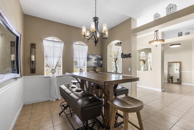 dining space with light tile patterned flooring and an inviting chandelier