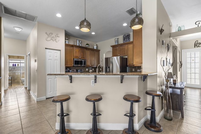 kitchen with a breakfast bar, kitchen peninsula, backsplash, and stainless steel appliances