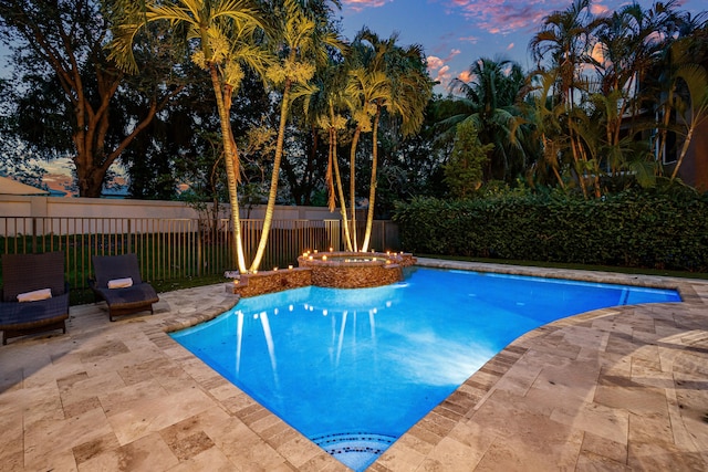 pool at dusk with an in ground hot tub and a patio area