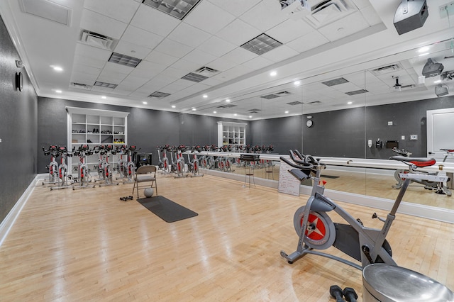 exercise room featuring crown molding, light hardwood / wood-style floors, and a drop ceiling