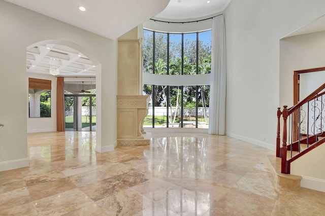 foyer entrance featuring beam ceiling, a high ceiling, and coffered ceiling