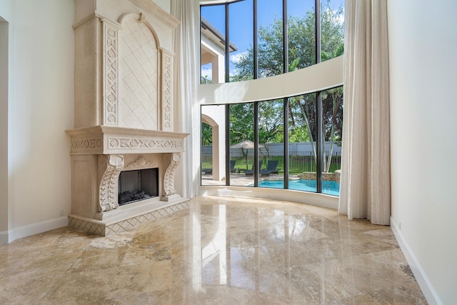 unfurnished living room with a fireplace and a towering ceiling