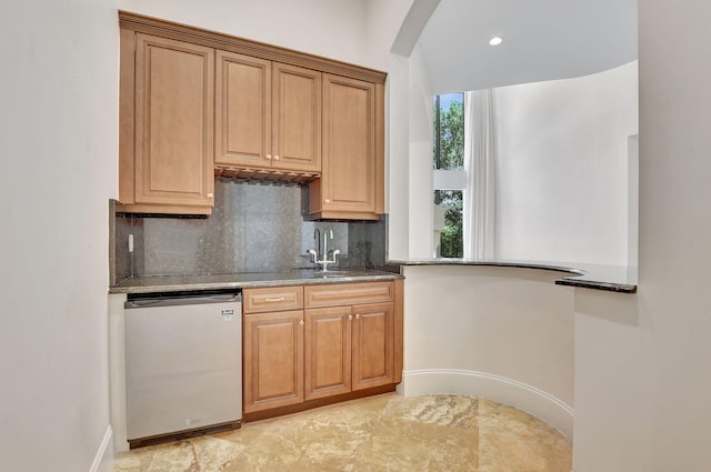 kitchen featuring tasteful backsplash, dishwashing machine, dark stone counters, and sink