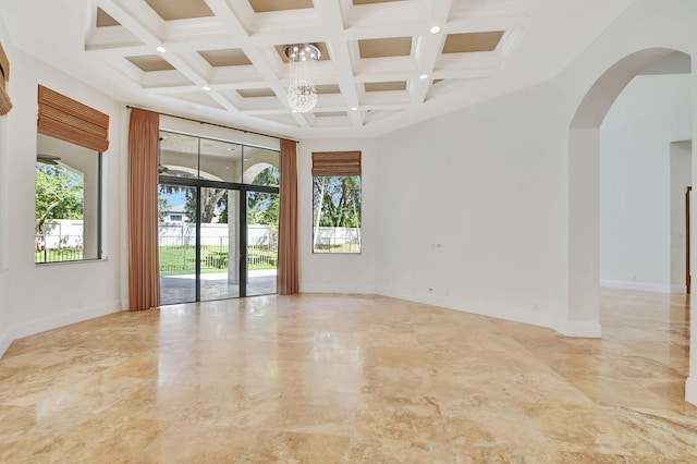 empty room with a high ceiling, a chandelier, beamed ceiling, and coffered ceiling