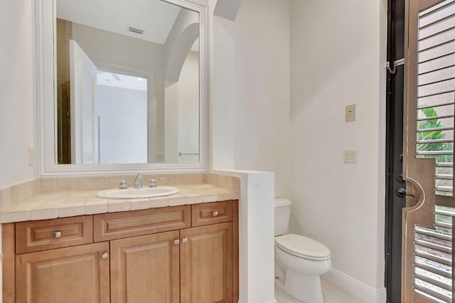 bathroom with toilet, vanity, and tile patterned flooring