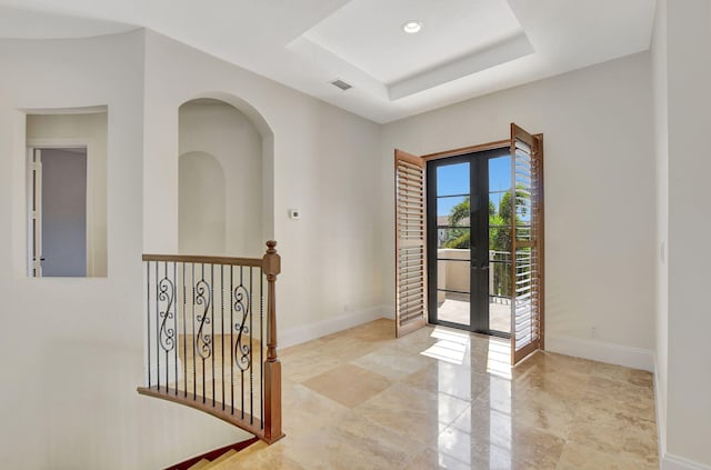 entrance foyer with a tray ceiling and french doors