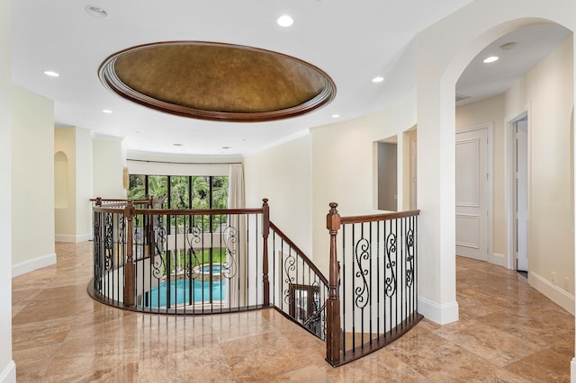 hall with a raised ceiling and crown molding