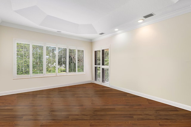 unfurnished room with a raised ceiling, dark hardwood / wood-style floors, and ornamental molding