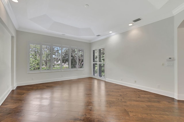 empty room featuring dark hardwood / wood-style flooring, crown molding, and a tray ceiling