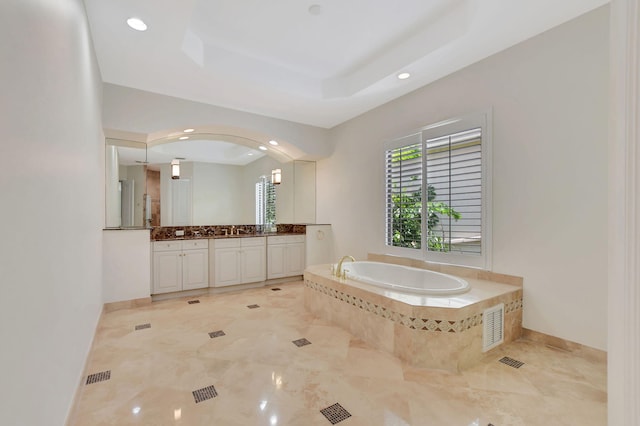 bathroom with a relaxing tiled tub and vanity