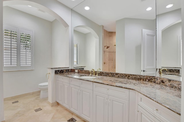 bathroom with tile patterned flooring, toilet, tiled shower, and vanity