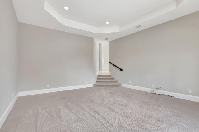 empty room featuring light colored carpet and a tray ceiling