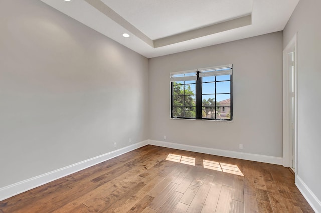 empty room with a tray ceiling and hardwood / wood-style floors