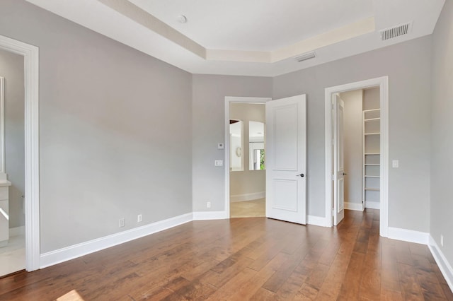 unfurnished room featuring a tray ceiling and dark hardwood / wood-style flooring