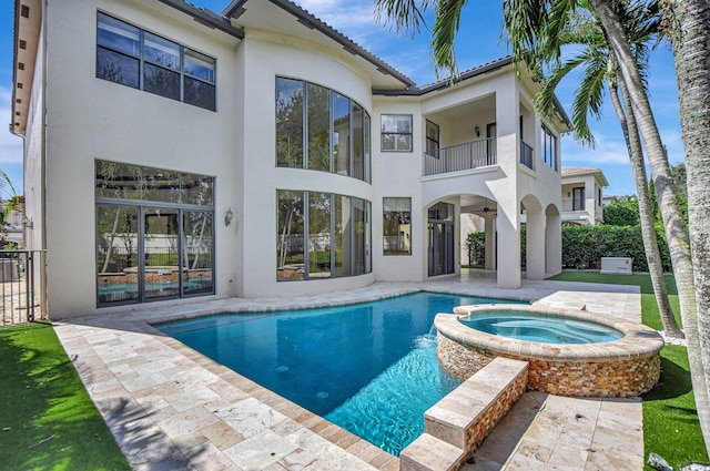 back of house with a swimming pool with hot tub