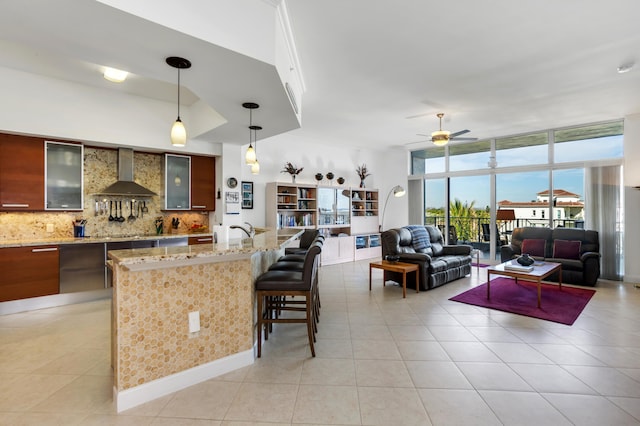 kitchen featuring expansive windows, light tile patterned floors, pendant lighting, decorative backsplash, and wall chimney range hood