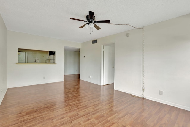 empty room featuring hardwood / wood-style flooring, sink, a textured ceiling, and ceiling fan