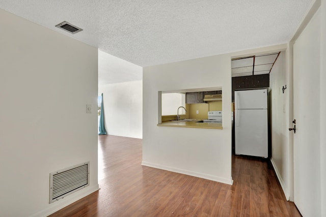 interior space with white appliances, a textured ceiling, sink, dark hardwood / wood-style floors, and kitchen peninsula