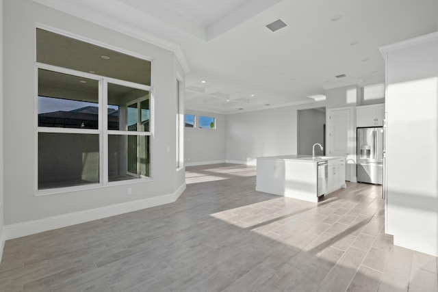 kitchen with white cabinetry, sink, ornamental molding, a kitchen island with sink, and stainless steel appliances