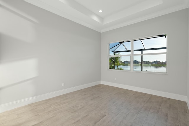 empty room featuring a water view, a raised ceiling, and light hardwood / wood-style floors