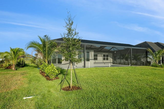 rear view of house with a lanai and a lawn