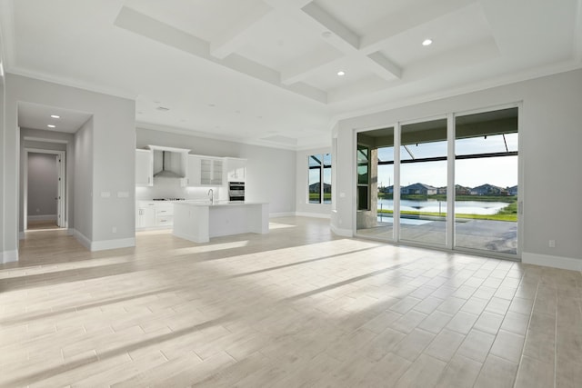 unfurnished living room featuring sink, a water view, coffered ceiling, light hardwood / wood-style floors, and beamed ceiling