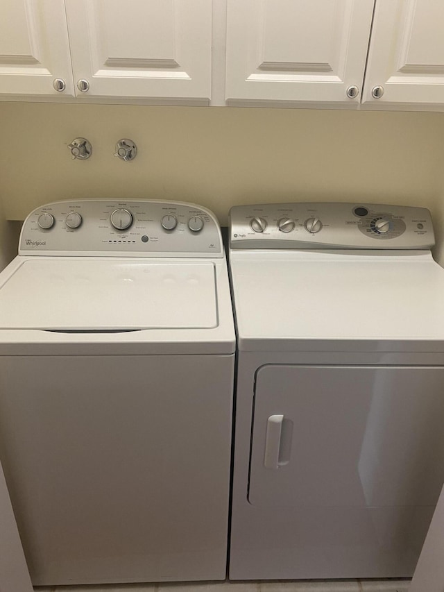 clothes washing area featuring cabinets and washer and clothes dryer