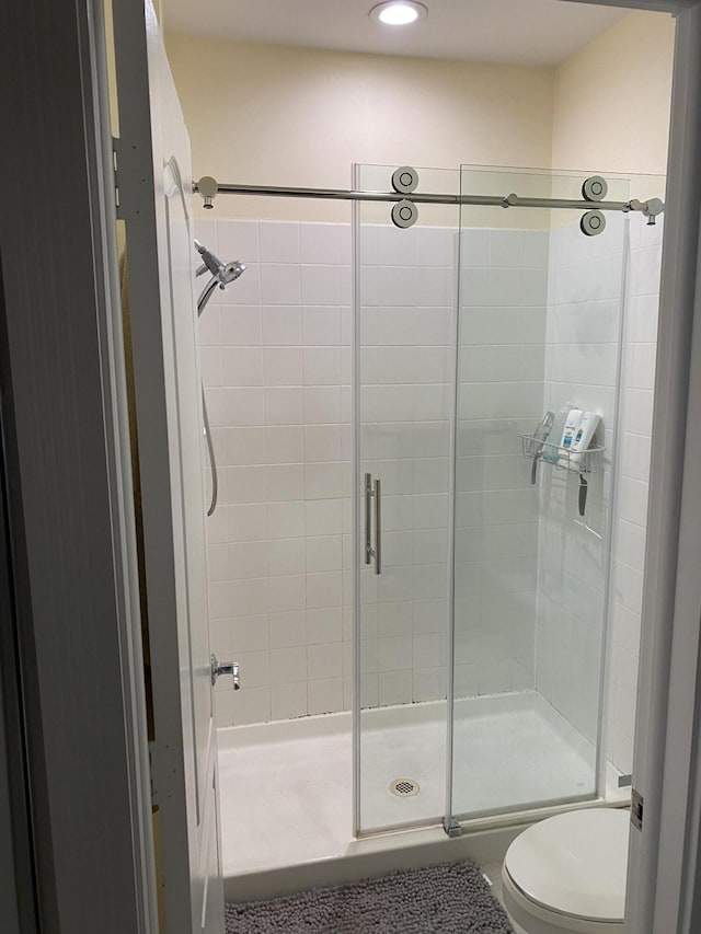 bathroom with toilet and a shower with shower door