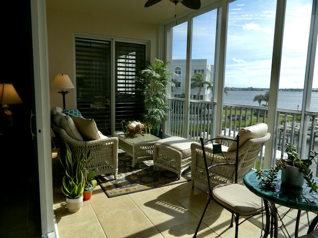 sunroom featuring ceiling fan and a water view