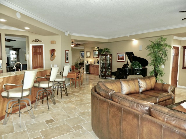 living room with crown molding, ceiling fan, sink, and a textured ceiling