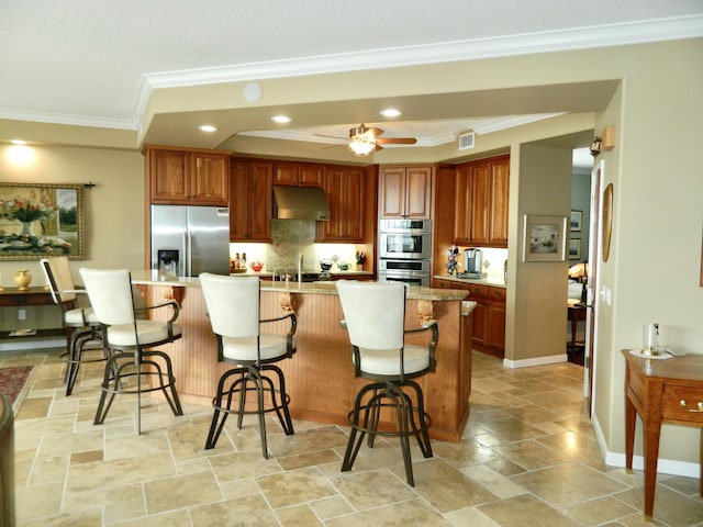 kitchen with stainless steel appliances, ornamental molding, a kitchen island, and a kitchen bar