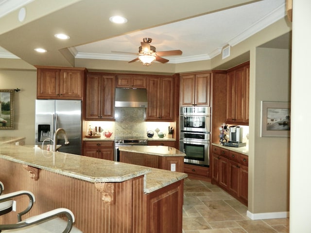 kitchen featuring light stone counters, appliances with stainless steel finishes, a breakfast bar, and kitchen peninsula