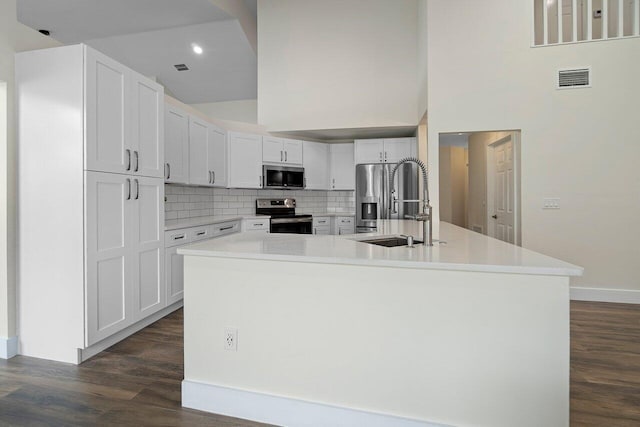 kitchen with white cabinetry, stainless steel appliances, sink, and an island with sink