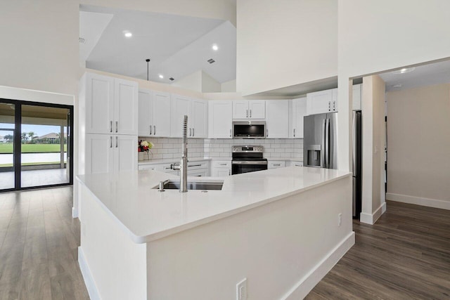 kitchen featuring a spacious island, appliances with stainless steel finishes, white cabinetry, tasteful backsplash, and high vaulted ceiling