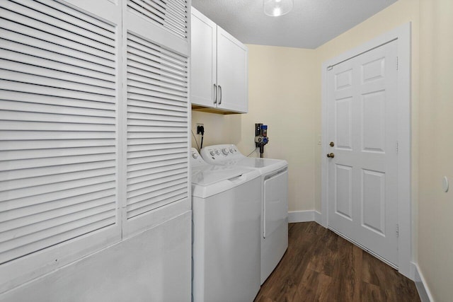 laundry room with dark wood-type flooring, cabinets, a textured ceiling, and washing machine and clothes dryer