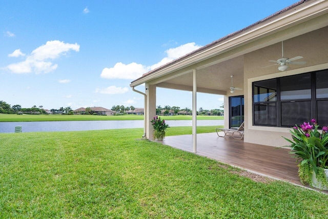 view of yard with ceiling fan and a water view