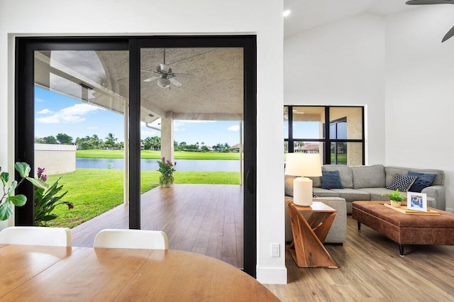 doorway to outside with a water view, ceiling fan, wood-type flooring, and a towering ceiling