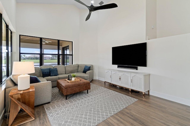 living room featuring hardwood / wood-style floors, ceiling fan, and a high ceiling