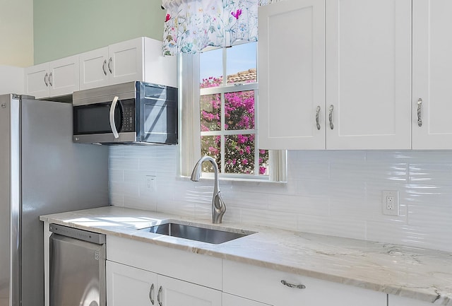 kitchen featuring tasteful backsplash, sink, white cabinets, stainless steel appliances, and light stone countertops