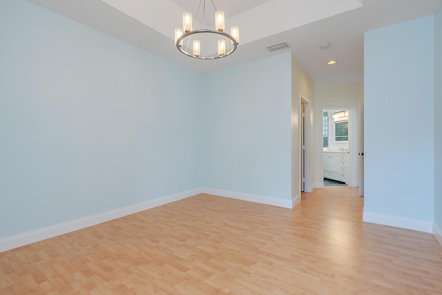 spare room featuring an inviting chandelier and light hardwood / wood-style floors