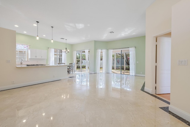 unfurnished living room featuring an inviting chandelier and sink