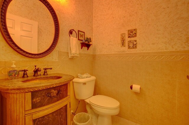 bathroom featuring toilet, vanity, and tile walls