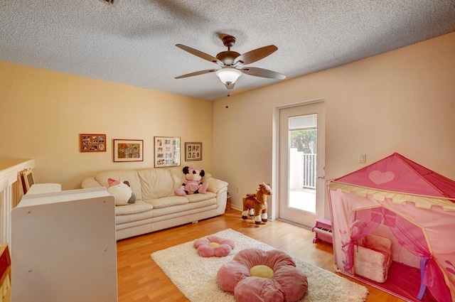 interior space with a textured ceiling, ceiling fan, and light hardwood / wood-style flooring