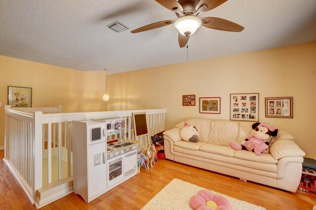 bedroom with ceiling fan, light colored carpet, multiple windows, and a textured ceiling