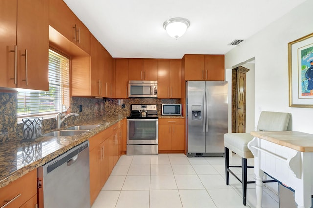 kitchen featuring stainless steel appliances, tasteful backsplash, sink, stone countertops, and light tile patterned flooring