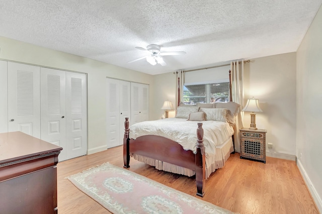 bedroom featuring ceiling fan, light hardwood / wood-style floors, a textured ceiling, and multiple closets