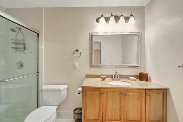 bathroom with toilet, vanity, and a shower with shower door